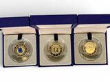 three gold coins are in a blue box with a blue ribbon