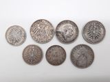 six types différents de pièces d'argent sur une surface blanche