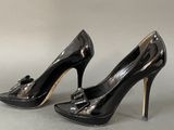 pair of black high heeled shoes with a bow on the toe
