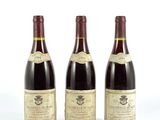 trois bouteilles de vin sont alignées sur une surface blanche