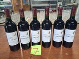 six bouteilles de vin rouge sont alignées sur une table