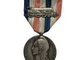 une vieille médaille en argent ornée d'un ruban rouge, blanc et bleu