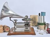 un gramophone argenté posé sur un socle en bois