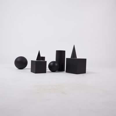 several black geometric shapes are arranged on a white surface