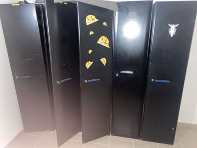 three black refrigerators with stickers on them in a room