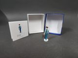 une petite figurine représentant un homme debout devant une boîte