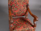 an old chair with a red and green floral upholstered seat