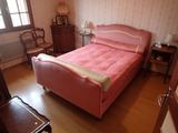 un lit rose dans une chambre, près d'une fenêtre