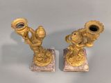 two gold colored candlesticks on a marble base