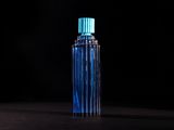 a blue bottle of perfume sitting on top of a black table