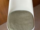 a white chair with a green cushion on it in a room