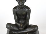 statue en bronze représentant un garçon assis à genoux sur un socle en marbre