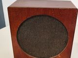 une petite enceinte en bois posée sur une table, avec un cordon
