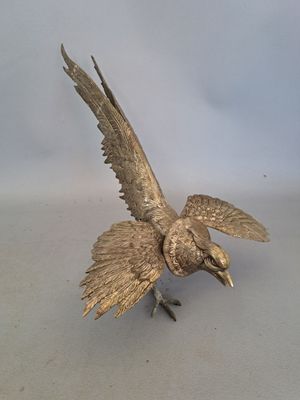 a bronze bird that is sitting on a table