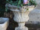 une jardinière en pierre remplie de fleurs roses, placée à côté d'un bol en pierre