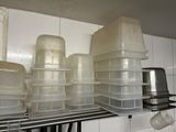 several plastic containers are stacked on a shelf in a kitchen