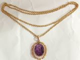 a close up of a necklace with a purple stone on it