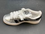 silver and black adidas sneakers with white laces on a gray surface