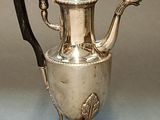 an antique silver tea pot with a black handle and a black handle