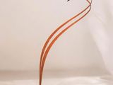 une sculpture en métal représentant deux oiseaux, posée sur un socle en bois