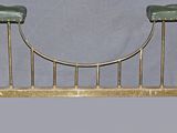 a gold metal bench with a green cushion on it