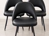 trois chaises noires aux pieds noirs, avec un mur blanc en arrière-plan