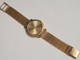 a close up of a gold watch on a white surface