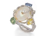 un gros plan d'une bague ornée d'une perle et de pierres multicolores