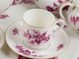 several cups and saucers are sitting on a table with pink flowers
