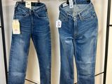deux paires de jeans suspendues à un portant dans un magasin de vêtements