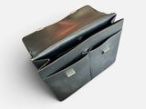 a black purse sitting on top of a table next to a white wall