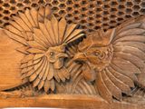 a wooden carving of a bird and a bird on a table
