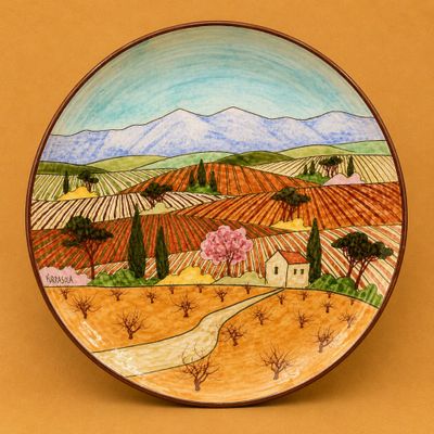 une image représentant une assiette sur laquelle est peinte une vue de campagne
