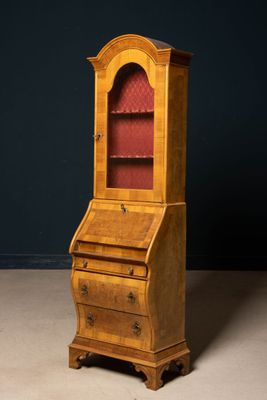 an old wooden bureau with a red glass door and drawers