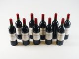 six bottles of red wine lined up in a row on a white surface