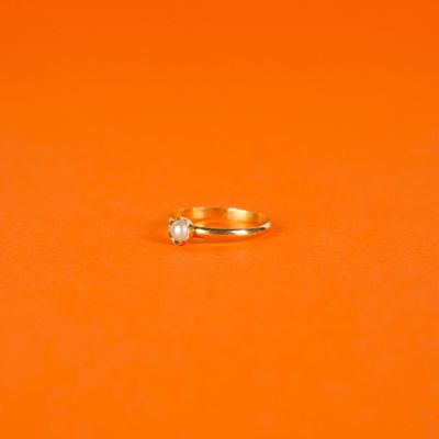 a gold ring with a diamond on an orange surface