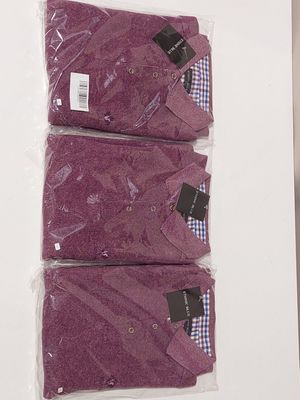three pairs of purple shirts sitting on top of a white table