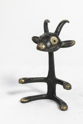 une petite statue de chèvre posée sur un socle