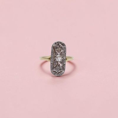 une bague ancienne sertie d'un diamant, sur fond rose