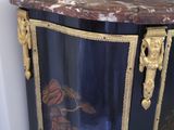 a black and gold cabinet with a painting on it