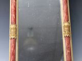 un miroir avec un cadre rouge et doré
