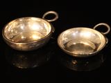 pair of silver plated bowls with handles on a black surface