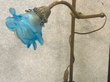 brass plated lamp with blue glass shade on a black table