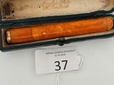 an orange pen in a black case on a white table