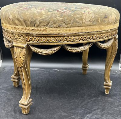 un repose-pieds de couleur dorée, dont l'assise est recouverte d'un tissu à motifs floraux