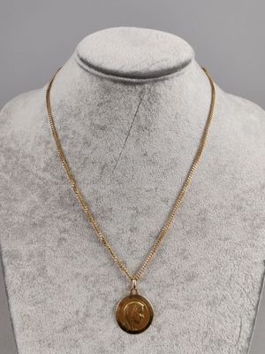 a gold necklace with a coin on a mannequin neck