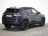 the back end of a blue jeep compass parked on a checkered floor