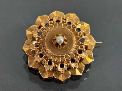une broche en or ornée d'une pierre blanche au centre