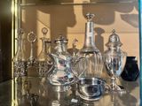 a lot of silver items on a glass shelf