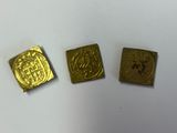 trois pièces d'or sont représentées sur une surface blanche